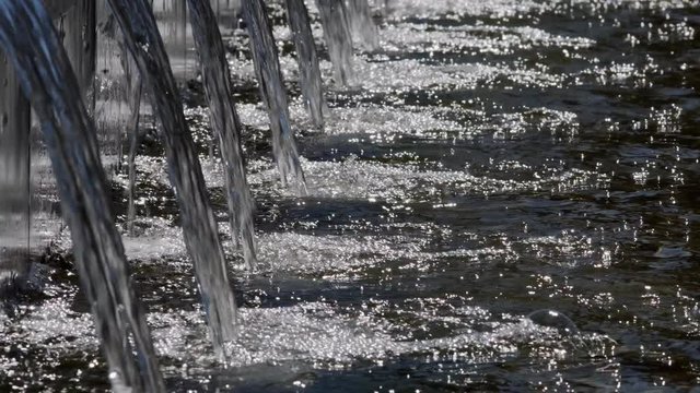 Modern urban water fountain strams gushing in a row on a bright sunny day.