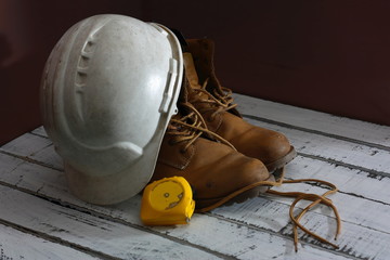 mis viejas botas de trabajo sobre unas maderas blancas, con mi casco y metro