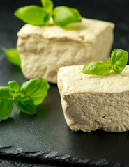 Organic Soy Tofu with basil on dark rustic stone board.