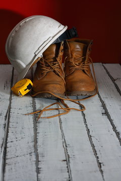 mis viejas botas de trabajo sobre unas maderas blancas, con mi casco y metro