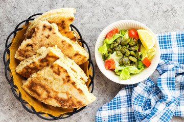 Algerian homemade bread named matlouh in arabic and salad bowl