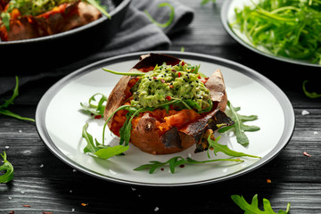 Baked Sweet potato boats stuffed with avocado guacamole and wild rocket sprinkled with nigella seeds