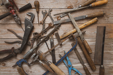 Vintage hand tools on a wooden background. Chaotic workdesk with many instruments. Carpentry, diy, craftsmanship concept, top view