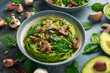 Vegan garlic mushroom pasta with spinach and avocado pesto drizzled with sesame seeds and roasted pine nuts