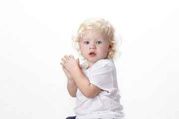 Blond Curly Haired Caucasian Toddler Boy with Blue Eyes Wearing White Shirt Sitting Down Facing Away Looking From Side
