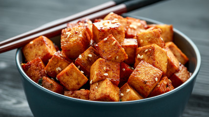 Fried Tofu in a bowl with chopstick and sesame seeds