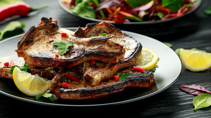 Homemade Grilled Pork loin chops in lemon sauce with herbs on rustic wooden table