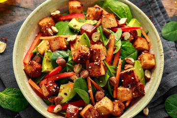 Healthy Vegan Fried Tofu salad with carrot, red bell pepper, spinach and nuts