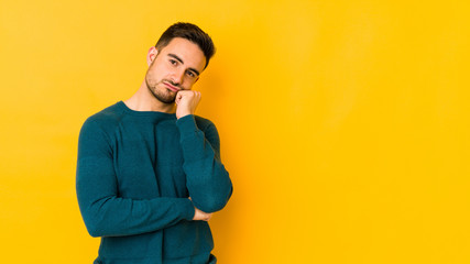 Young caucasian man isolated on yellow bakground tired of a repetitive task.