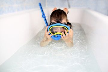 kid, boy dives with scuba gear and mask in the bath at home, happy childhood concept