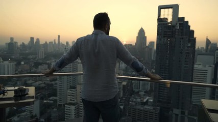 Young man admire beautiful sunset over city at luxury bar - Powered by Adobe