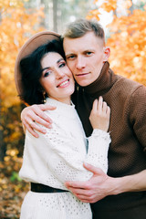 two happy lovers embrace each other in the middle of a pine forest in the autumn, around the Golden leaves on the trees