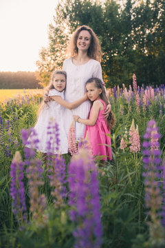 Woman and two girls together in a field with lupins