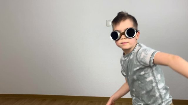 little boy in glasses selflessly dances a funny dance and fools around, creative concept