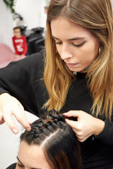 Fototapeta premium Hairdresser makes braid to client