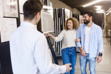 Obraz premium Happy and smiling couple choosing ceramic tile for house