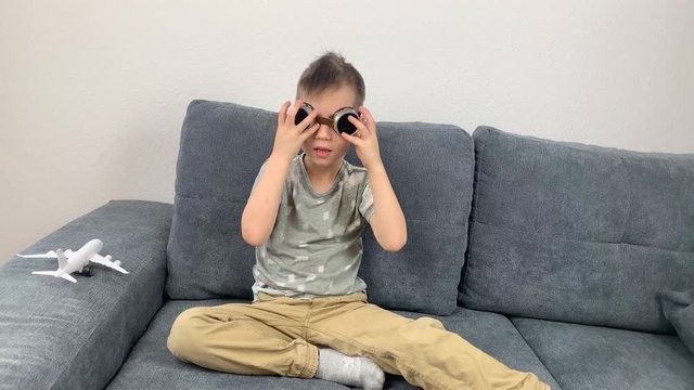 kid in black glasses plays with a white airplane toy, concept of flight, travel