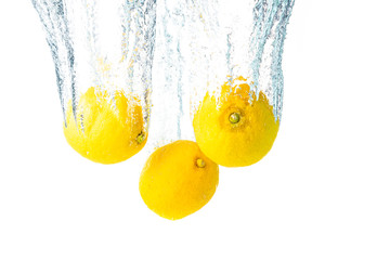 Lemons splash into water and sinking on white background.