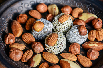 Various nuts are laid out in a brown handmade clay plate. Close up. Selective focus. 