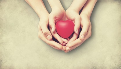 Adult and child hands holding the red heart