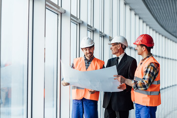 Business team talk with architectural plans on white panorama windows.