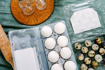 Chicken and quail eggs in the package on a blue background with a rolling pin