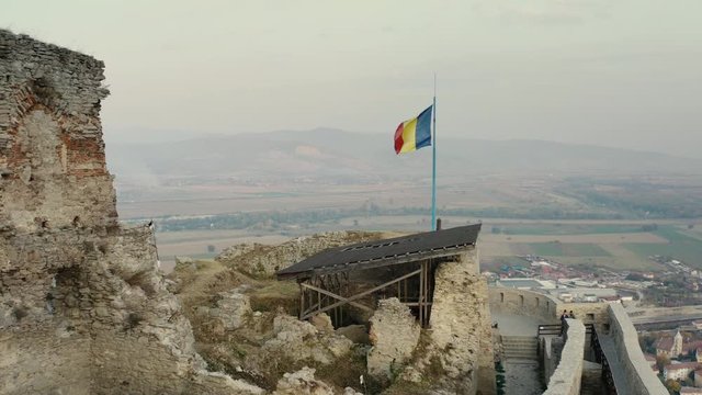 Aerial view of the Fortress Of Deva at sunset during fall.
Romanian flag on the Fortress Of Deva at sunset.