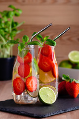Refreshing drink or water with strawberry, citrus fruits lemon, lime and basil in mason jar with reusable metal straws. Healthy lemonade drink in glass jar, zero waste concept, sustainable lifestyle