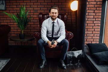 Stylish man reading business newspaper and sitting on couch.