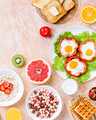 Continental breakfast with cereal, fried eggs, croissants, fruits and drinks on textured table, copy space. Table top with various healthy snacks and foods on rustic background