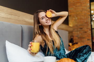 Portrait of a happy woman have a breakfast on bedroom with fresh orange juice.
