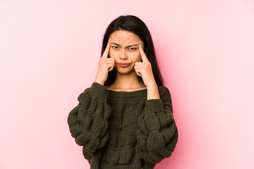 Young chinese woman isolated on a pink background focused on a task, keeping forefingers pointing head.