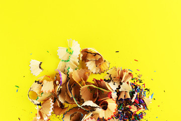 Naklejka premium colored pencils with scattered shavings on a yellow background.