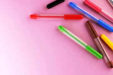multi-colored markers on a pink background
