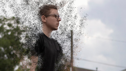 A young Caucasian man wearing a black t-shirt and glasses stares straight ahead from a side angle...