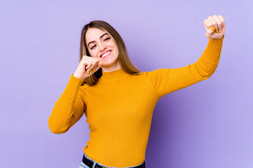 Young caucasian woman isolated on purple background dancing and having fun.