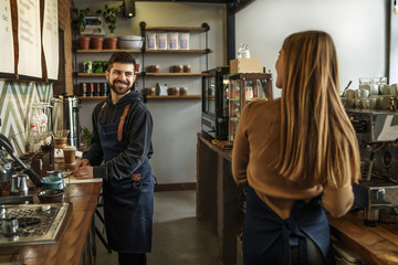 Professional barista team brewing coffee using coffee machine in coffee shop. Happy young man and woman developing own coffee business