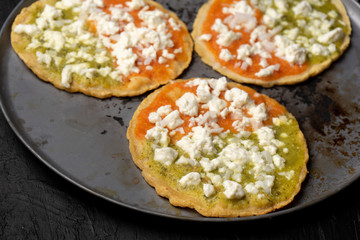 Mexican memela with green and red sauce on dark background