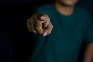 Young man showing finger it means make your choice on dark black background. selective focus on finger