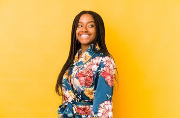Young african american woman wearing an asiatic pijama isolated looks aside smiling, cheerful and pleasant.