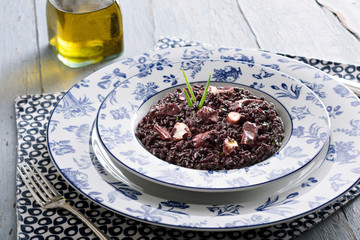 Table set for a dinner, with blue decorated portuguese plate. A octopus rice is being served, an typical portuguese dish, a traditional recipe very tasty and ideal for winter days.