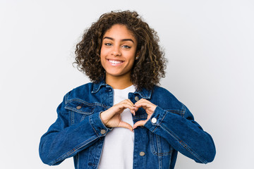 Young african american woman smiling and showing a heart shape with hands.