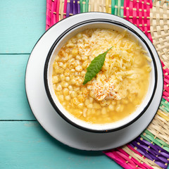Mexican corn grain boiled also called esquites with cheese and mayonnaise on turquoise background