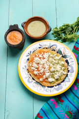 Mexican memela with green and red sauce on turqouise background