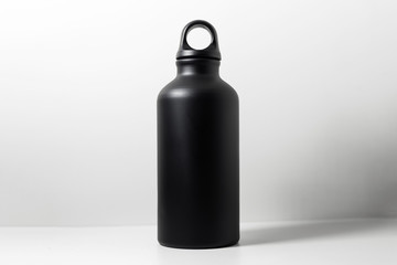 Close-up of black reusable aluminum eco thermo bottle for water on background of white.