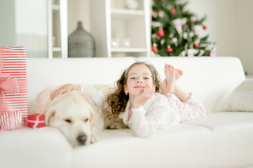 Obraz premium Cute little child with golden retriever dog enjoying Christmas atmosphere