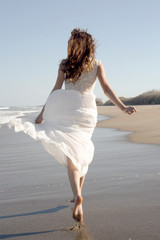 Fototapeta na wymiar Woman in White Dress Running on Beach