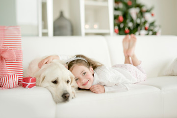 Cute little child with golden retriever dog enjoying Christmas atmosphere