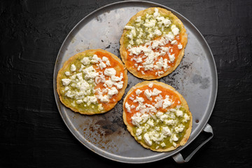 Mexican memela with green and red sauce on dark background