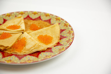 Beautiful plate with pancakes and caviar with close-up on a white background